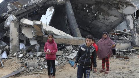 Children outside a destroyed building in Gaza