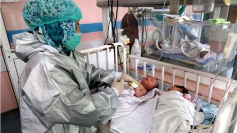 An Afghan nurse observes newborn children who lost their mothers during an attack at a hospital, in Kabul, Afghanistan, 13 May 2020