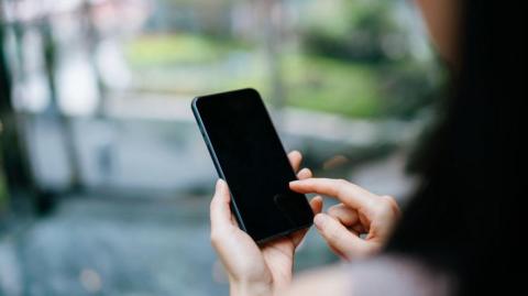 Over the shoulder view of woman using smartphone