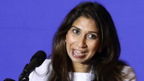 Suella Braverman head and shoulders shot against a blue background, as she speaks into a microphone on stage during the National Conservatism Conference on July 8, 2024 in Washington, DC.