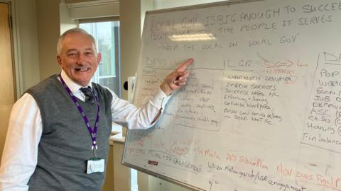 A council leader points at a whiteboard