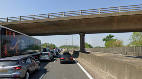 M25 in Surrey full of traffic with Cobham road bridge above
