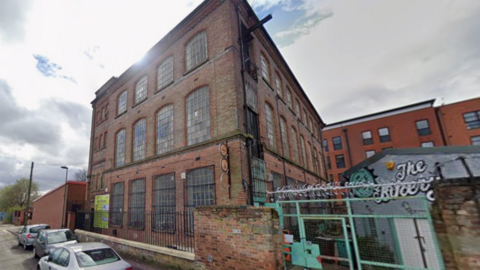 A Google Streetview image of the three-storey building in Ayr Street, which has a red brick facade, large panelled windows and a black fence at the front.