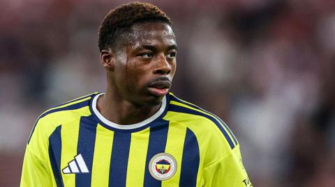 Anthony Musaba in action for Fenerbahce. He is wearing a yellow shirt with navy blue stripes