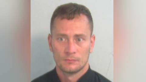 A slightly blurred police custody mugshot of Kieron Wright. He has short, dark hair, stubble and is looking slightly off-camera.