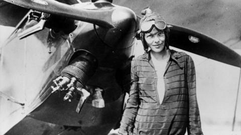 Amelia Earhart stands in front of her plane