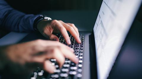 Hands typing on a laptop