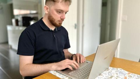 Joe Burgess on his lap top computer in his Felixstowe home looking for jobs
