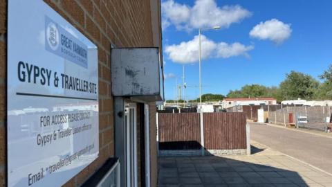 A sign bearing the crest of Great Yarmouth Borough Council, stating: "Gypsy and Traveller Site. For access please contact Gypsy and Traveller Liaison Officer on: obscured phone number and email address