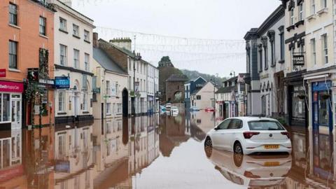 Cars stuck in flood water in a high street.