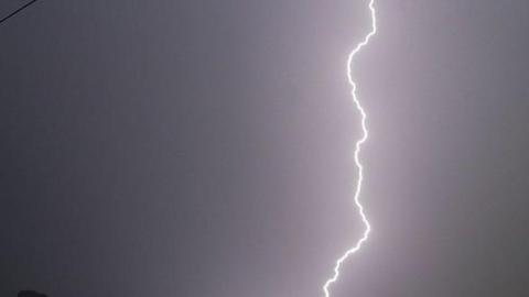 Stock photo of a dark sky with a jagged white line of lightning hitting the ground.