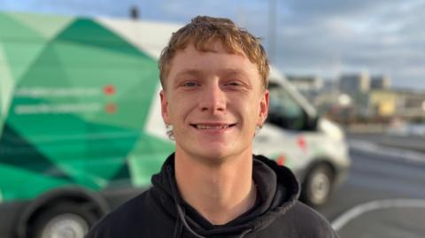 Etienne le Vallee - A young man with floppy ginger hair on his head. He is smiling at the camera and has a black hoody on.