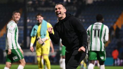 Wycombe manager Matt Bloomfield celebrates in front of the travelling fans at Stockport