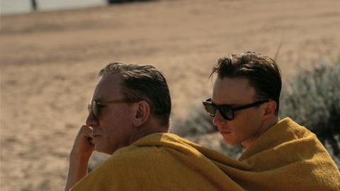 Two men in a desert with a blanket over them
