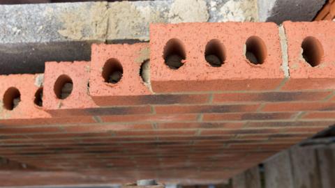 Aerial view of a incomplete house wall under construction, showing a layer of breeze blocks and bricks