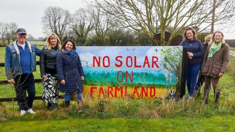 Six people standing by a banner reading: 'No Solar on farmland'