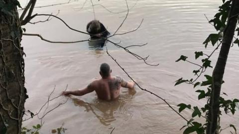 Man wades into floodwater to save woman