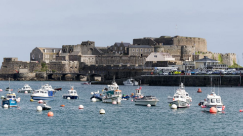 Castle Cornet in the background and moored boats in the foreground on an overcast day