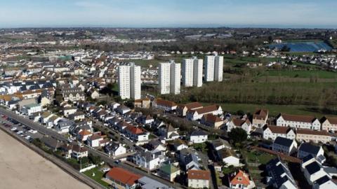 A photo of Jersey. On the left it shows the beach and then a number of houses in the distance.