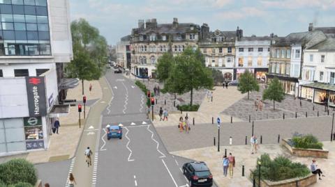 A digitally drawn image of a town centre, from the point of view of above. A road runs through the middle, from the bottom of the image into the distance. To its left is a large pavement and a white high building, the train station, with glass windows. It has a sign, on its side, reading "Harrogate" with the national railways symbol. To the right of the road is a taxi rank and a large pedestrianised town square, with no cars, just lots of people million around freely. There are flowerbeds and trees incorporated into the paved area. There are tall, old-looking buildings with new-looking shops at the ground level around the square. People are using the pavements, cycle lanes and seating areas.