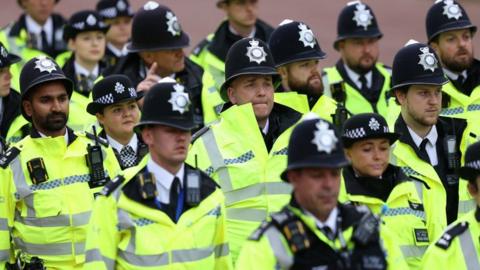 Police officers in hi-vis jackets walk down the Mall during a Coronation event.