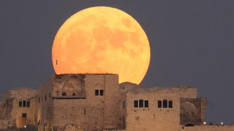 Moon rising over buildings
