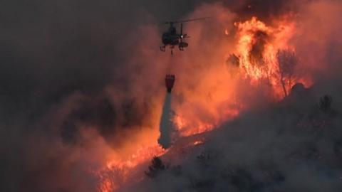 A helicopter drops water on the wildfire near Vitrolles