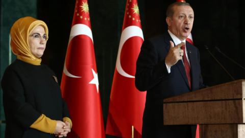 Turkish President Recep Tayyip Erdogan delivers a speech, flanked by his wife Emine, in Ankara on February 9, 2016.