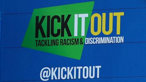 The Kick It Out logo on the side of a stand in a football stadium