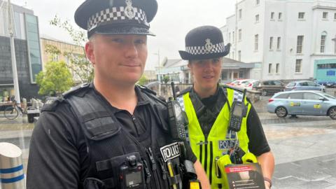 PC Mike Smith and PC Chantelle Wildman stood on a street in the rain.