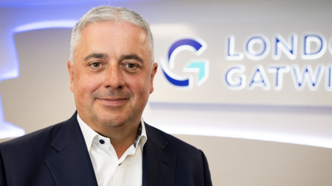 A close up image of Stewart Wingate in front of a London Gatwick sign
