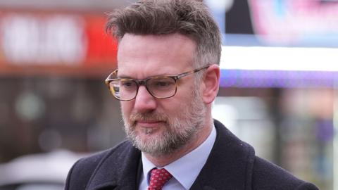 An image of tv auctioneer Charles Hanson entering Derby Crown Court while wearing a red tie and navy blue coat