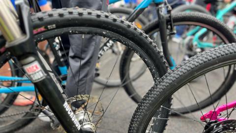Bicycle wheels lined up on a piece of tarmac.