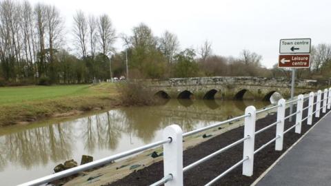 River Stour flowing under the Sturminster Newton Bridge with cars travelling across the stone bridge.