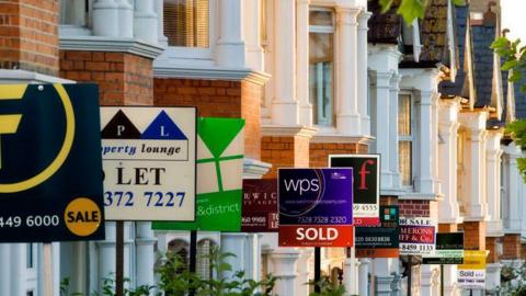 Row of houses with for sale signs outside