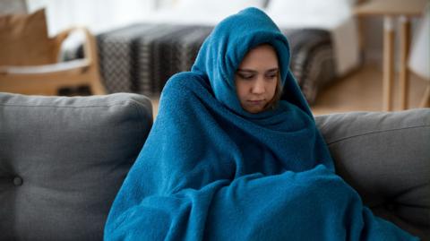 A woman wrapped in a blue blanket