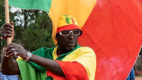 A Malian waving a flag as he attends a campaign rally