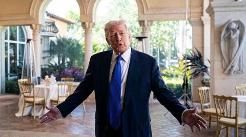 US President Donald Trump stands and gestures with his hands