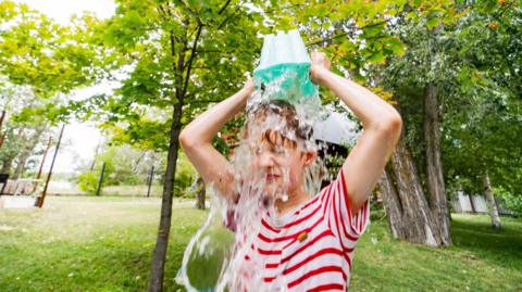 child pouring bucket of water over their head