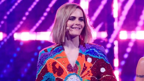 Hazel Brugger at the Eurovision Song Contest 2025 - she wears a multicoloured beaded jacket 