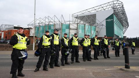 A row of police officers wearing hi-viz vests lined up outside Celtic Park