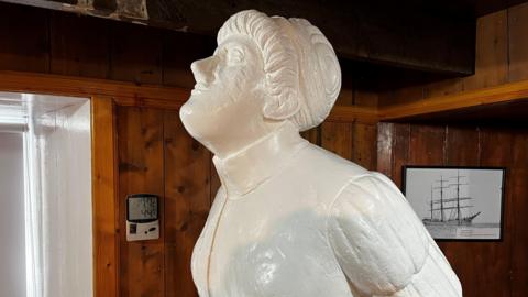 The figurehead portrays a woman with her hair tied up and her head looking up towards the sky.