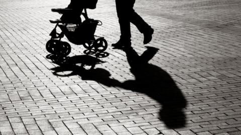 Silhouette of a parent pushing a pram