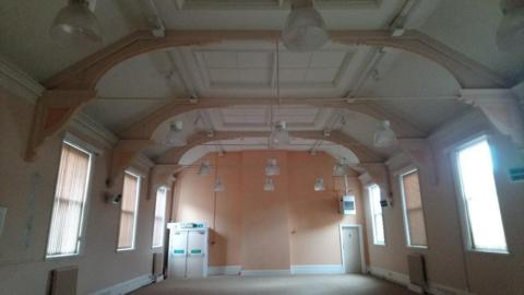 An empty hall with lighting and windows with the blinds drawn