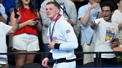 Adam Peaty holds his medal while crying