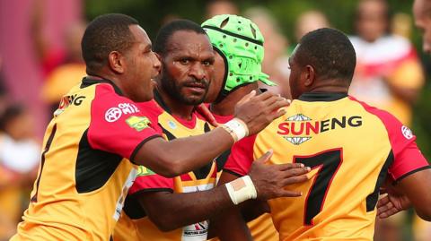 Four PNG players congratulate themselves at a trial match in Sydney in 2013