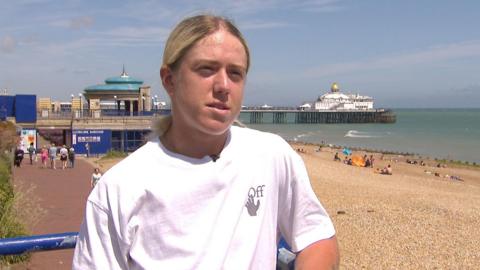 Sonay Kartal stands on Eastbourne seafront, wearing a white t-shirt, with the pier and beach in the background.