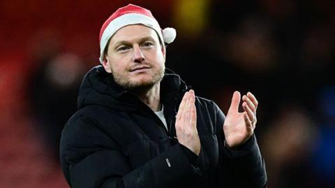 Kim Hellberg, wearing a red Christmas hat, claps Middlesbrough fans after the win over QPR