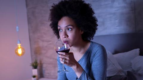 A woman drinking a glass of wine at night