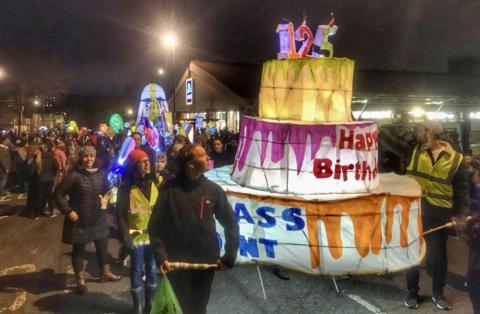 People walk through the streets of Bedminster carrying a giant illuminated paper birthday cake as part of the annual winter lantern parade